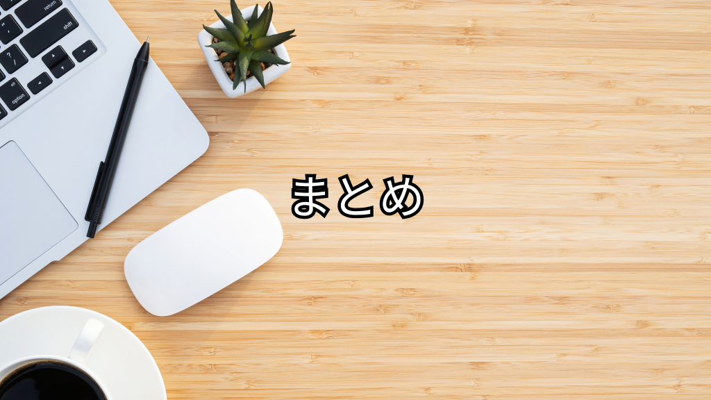 木の机の上にパソコンやペン、観葉植物、コーヒーが置いてある